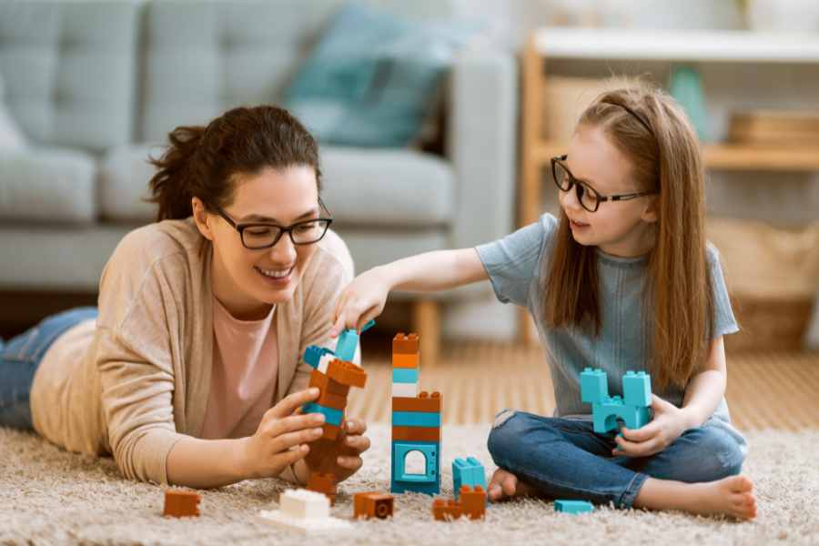 Young girl and woman playing with colourful toy blocks
